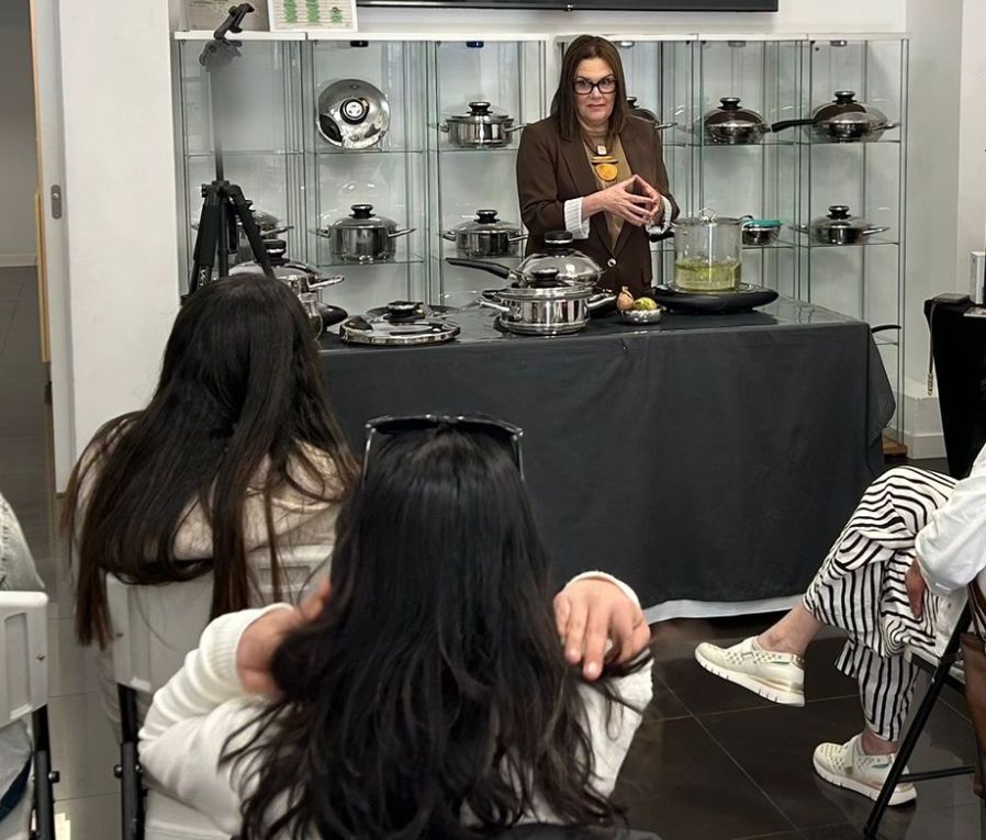 Charo Coromoto explica una receta delante de un grupo de alumnas sentadas durante un taller de cocina